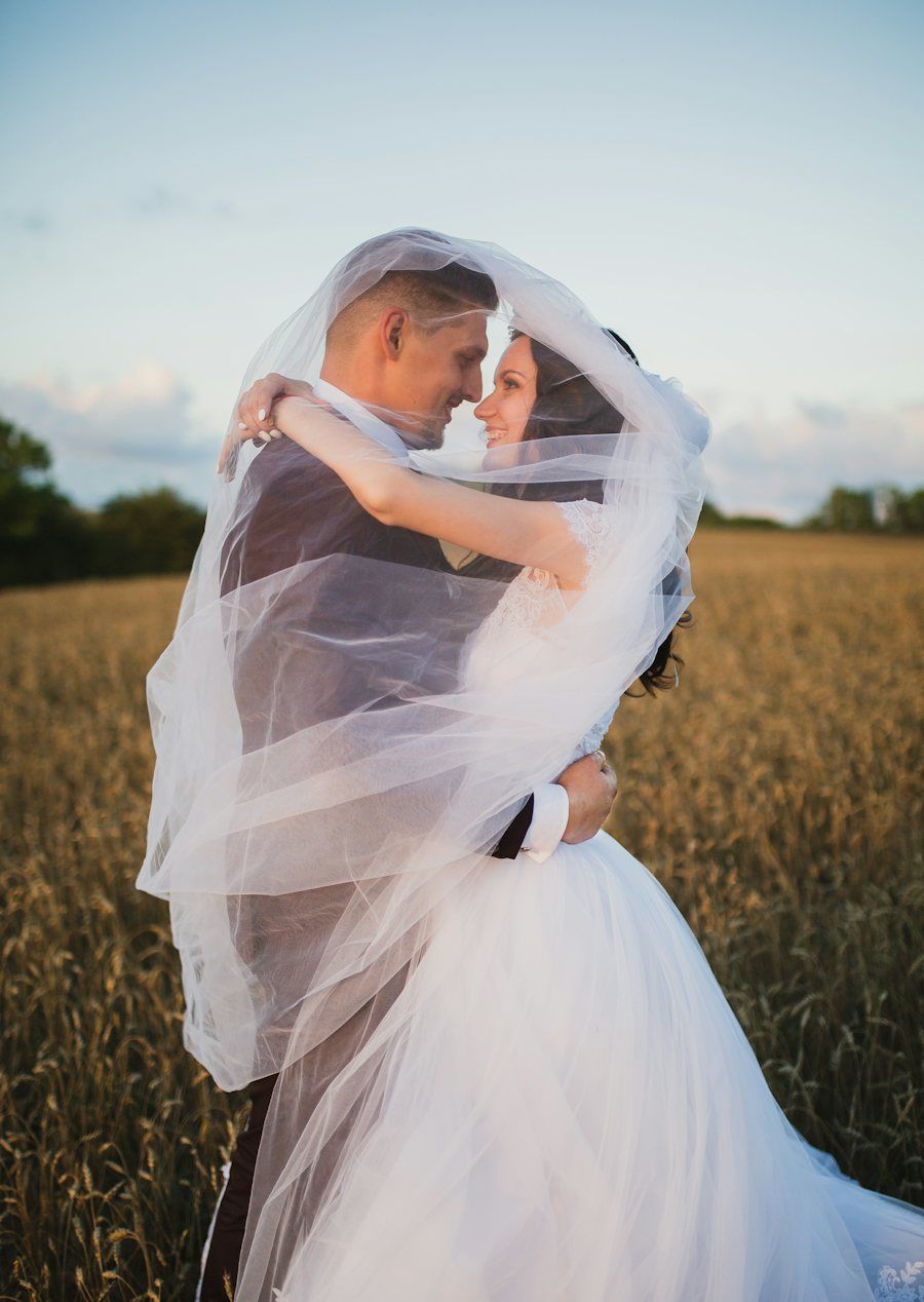 Couple under a wedding veil in a field